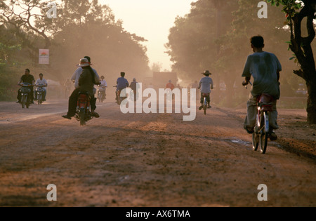 People commute on bicycles on a dusty road near Siam Reap in Cambodia very close to Angkor Wat temple Stock Photo