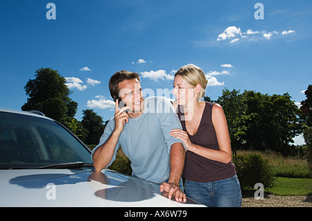 Couple by car using mobile phone Stock Photo