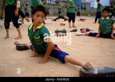 A young Chinese boy practices kung fu stretching at the Ta Gou kung fu school in Shaolin Stock Photo