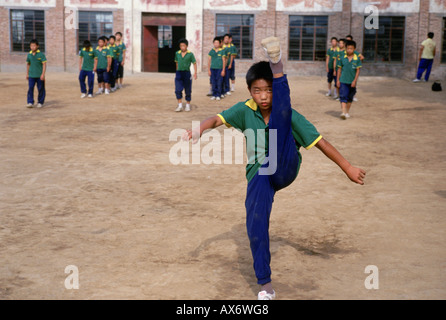 A young Chinese boy practices kung fu kicking at the Ta Gou kung fu school in Shaolin Stock Photo