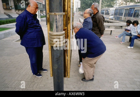 Chinese men in traditional Mao suits with Mandarin collars in Beijing read newspapers posted on a publc board Stock Photo