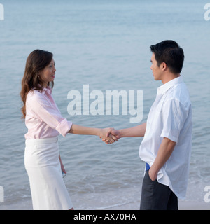 Side profile of a mid adult man and a mid adult woman shaking hands Stock Photo