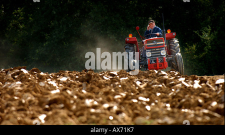 Farmer on old red tractor ploughing field. Picture by Jim Holden. Stock Photo