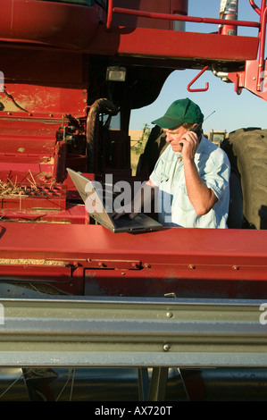 Farmer working on laptop computer, using cell phone. Stock Photo