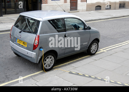Electric car plugged into extension cord for recharging on street, City of Westminster, London SW1, Engand Stock Photo