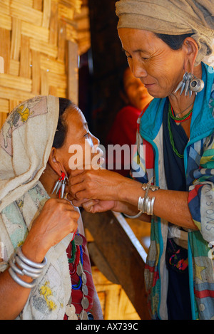 Red Karen hilltribe women adjust earrings Burmese refugee village north Thailand Stock Photo
