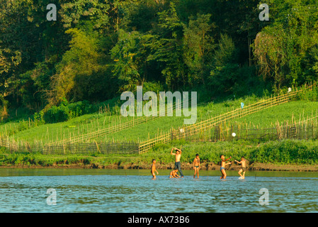 Children cool off in the Khan River beside small riverside vegetable plots Luang Prabang Laos Stock Photo