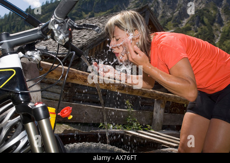 Austria, Salzburger Land,Young woman splashing water at a fountain Stock Photo