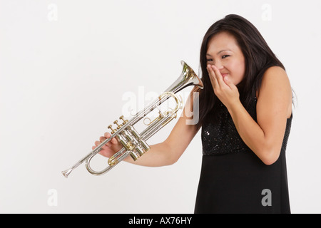 Stock Photograph of a Asian girl laughing while playing with a trumpet Stock Photo