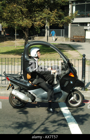 London man in office suit driving a motor scooter waiting at traffic lights Stock Photo