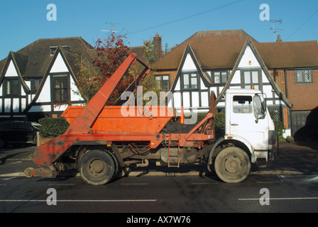 Builders skip lorry parked in road outside houses Stock Photo