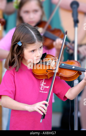 Violin strings group made up of children play a recital outside for the public Stock Photo