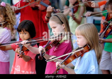 Violin strings group made up of children play a recital outside for the public. Stock Photo