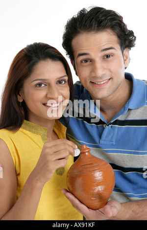 Portrait of a couple holding a piggybank and saving money Stock Photo