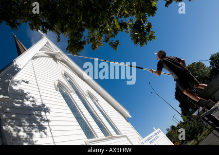 man standing on top of van spray washing church Stock Photo