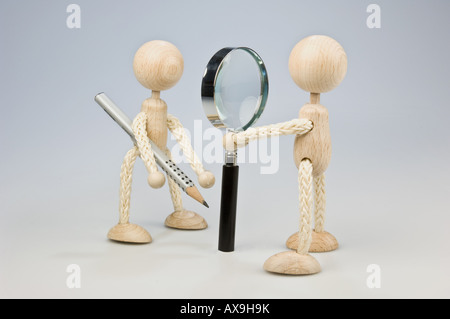 Two wooden figures with magnifying glass and pencil Stock Photo