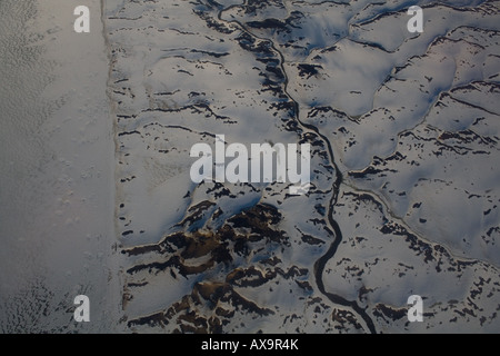 abstract arial photograph of a river on the coast Greenland with snow covered rolling hills and melting sea ice. Stock Photo