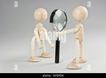 Two wooden figures with magnifying glass Stock Photo