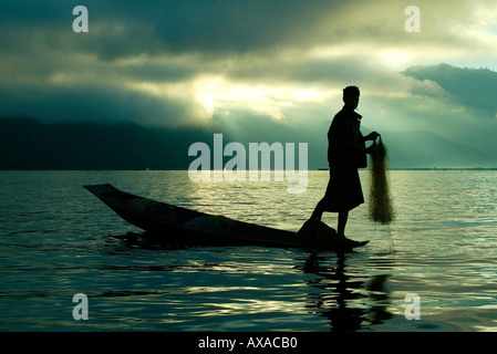 Man fishing from boat with hand-net at dawn Inle Lake in Burma Myanmar Stock Photo