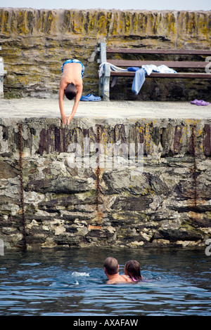 A boy dives in to the sea at Polperro Harbour, Cornwall Stock Photo