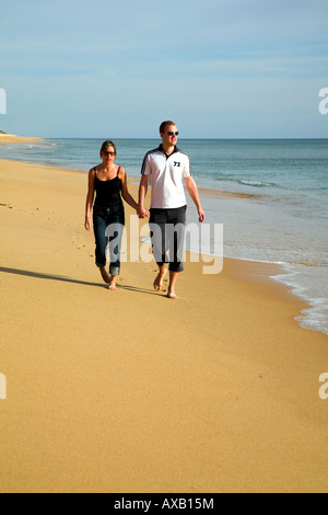 Young couple strolling together along a sandy beach. Stock Photo