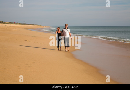 Young couple strolling together along a sandy beach. Stock Photo
