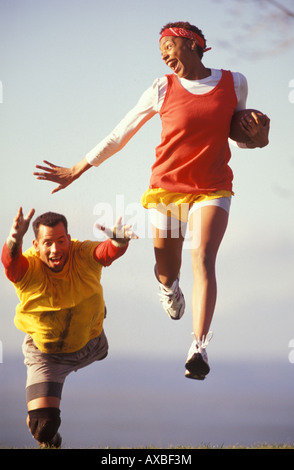 An African American couple of college students play a vigorous game of touch football Stock Photo