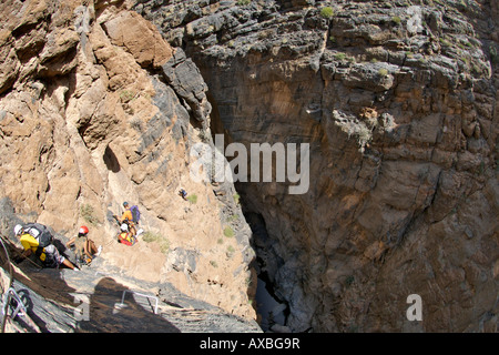 Hikers doing the Via Ferrata hike in Snake Canyon, part of Wadi bani auf in Jebel Akhdar of the western Hajar mountains in Oman. Stock Photo