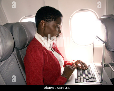 Young woman working on laptop on a airplane Stock Photo
