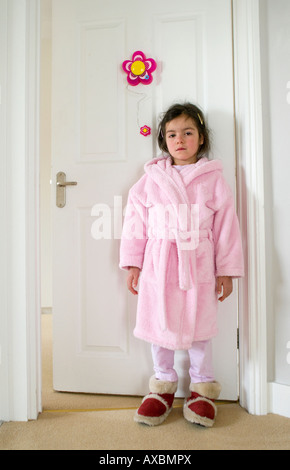 Sick child stands outside  bedroom door wearing gown Stock Photo
