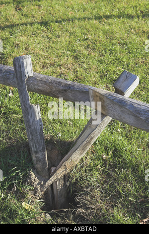 Vertical image of split rail fence, broken in country setting with grass lawn Stock Photo