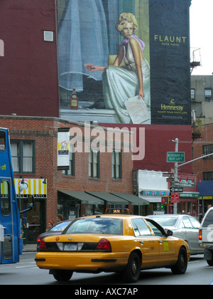 New York taxi in traffic sourrounded by high rise buildings, big painted advertising on the wall of a house, USA, Manhattan, Ne Stock Photo