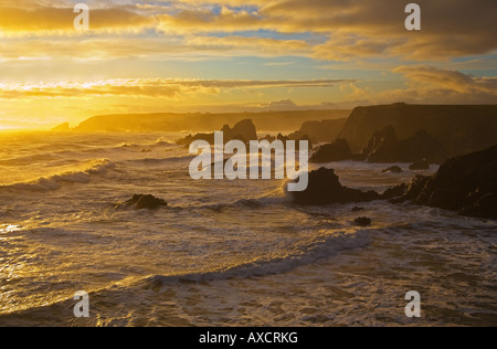 Westerly view of the sun setting over the sea, from Stage Cove, Bunmahon, The Copper Coast, County Waterford, Ireland Stock Photo