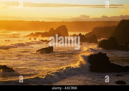 Westerly view of the sun setting over the sea, from Stage Cove, Bunmahon, The Copper Coast, County Waterford, Ireland Stock Photo