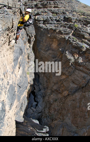 A man doing the Via Ferrata hike in Snake Canyon, part of Wadi Bani Auf in Jebel Akhdar of the western Hajar mountains in Oman. Stock Photo