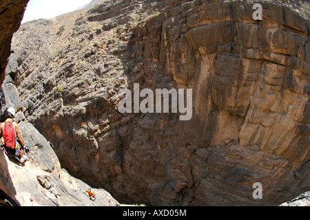 Hikers doing the Via Ferrata hike in Snake Canyon, part of Wadi Bani Auf in Jebel Akhdar of the western Hajar mountains in Oman. Stock Photo