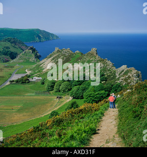 Middle aged couple with man pointing west over rugged green peaks at beauty spot of Valley of Rocks North Devon England Stock Photo