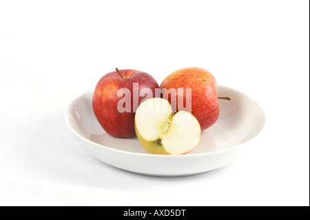Two and a half apples in a white bowl on a white background Stock Photo