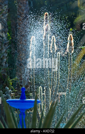 Vertical close up of a bright blue fountain with a jet of water glistening in the sun. Stock Photo