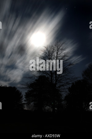 Moon (at the vernal equinox) peeping out from behind beautiful clouds. Motion is movement of the clouds over extended exposure Stock Photo