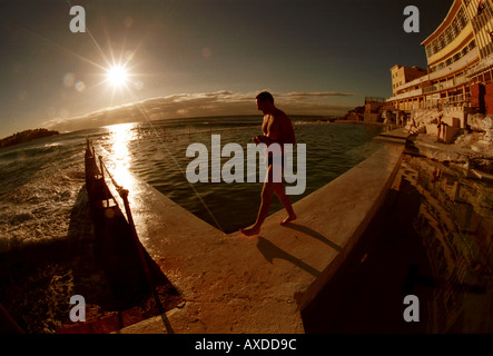 Man walking around Bondi Ice Bergs sea pool at Sunrise Stock Photo