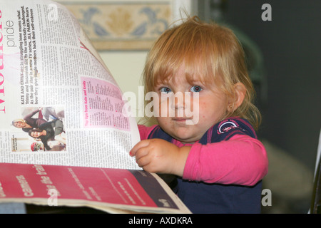 Two year old little girl attempting to read magazine. Stock Photo