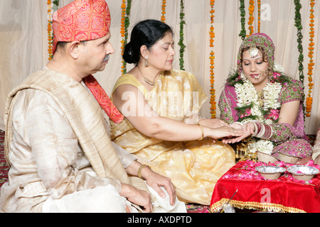 Bride getting married with her parents sitting besides her Stock Photo