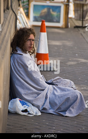 Candid picture of a man begging on a street in Edinburgh, Scotland. Wrapped in a blanket to keep him warm. Stock Photo
