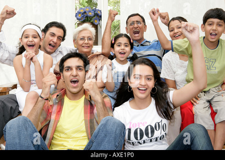Joint family watching television and cheering Stock Photo