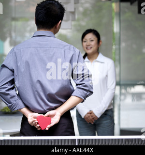 Rear view of a man holding a gift box behind his back, a woman in the background Stock Photo