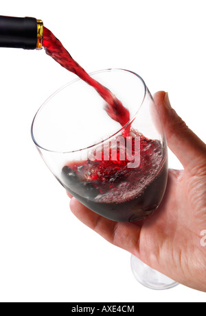 Red wine being poured into a wine glass being held by a man's hand against a white background Stock Photo