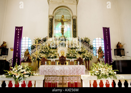 Altar with black Christ and flowers in Catholic church Juayua El Salvador Stock Photo
