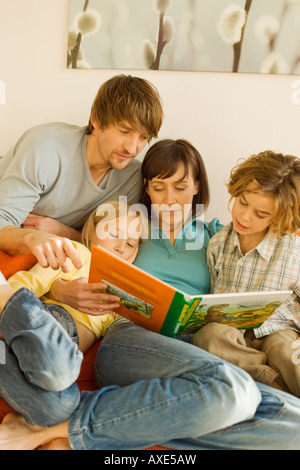 Family reading story book in living room Stock Photo