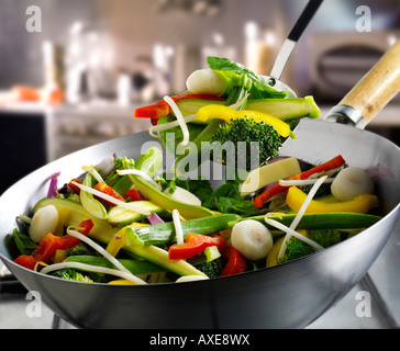 Vegetable stir fry in a wok being stirred with courgette, brocoli, bean shoots and vegetables Stock Photo